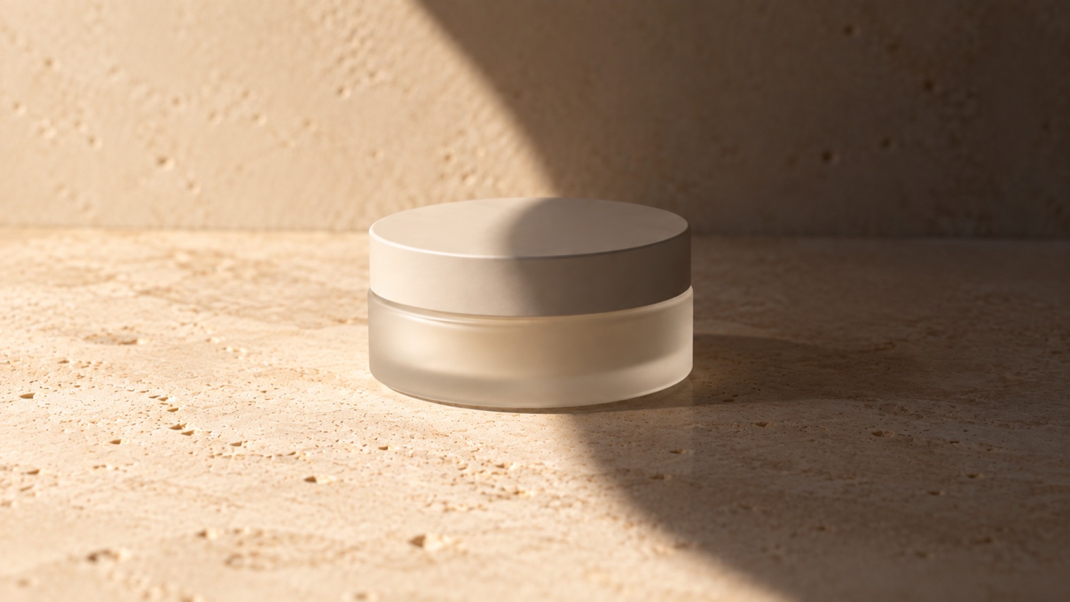 A plain matte jar half in bright daylight and half in deep shade, the division curving across pale stone.