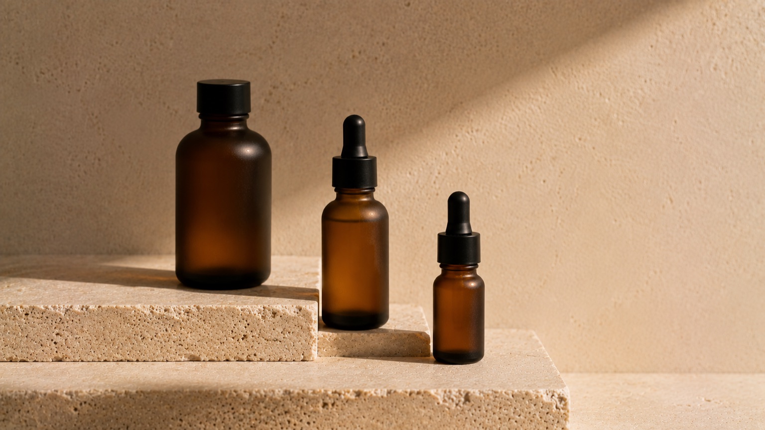 Three plain amber bottles of different sizes standing on a stepped stone ledge, lit from one side.